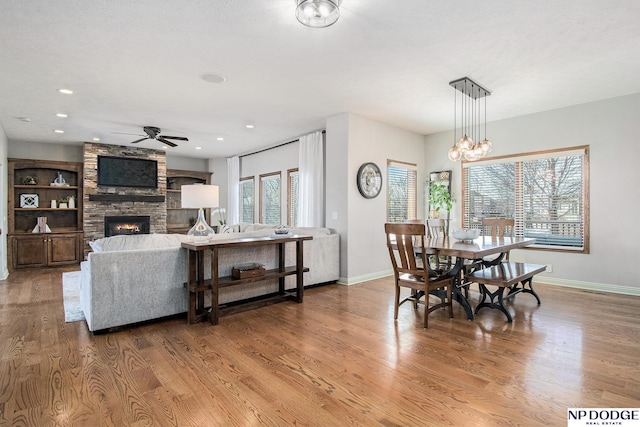 dining area featuring wood finished floors, baseboards, a fireplace, recessed lighting, and ceiling fan with notable chandelier