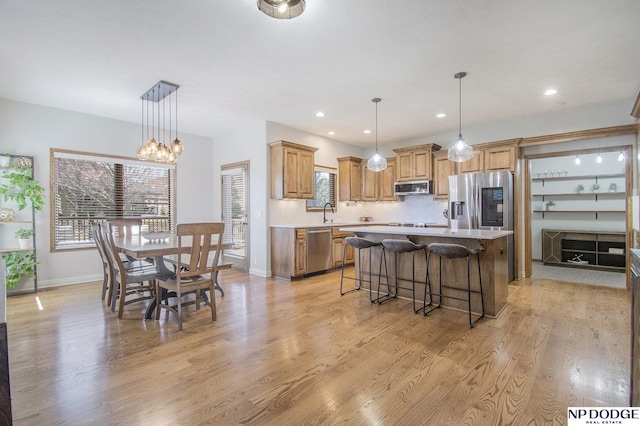 kitchen with a kitchen bar, light wood finished floors, a center island, stainless steel appliances, and light countertops