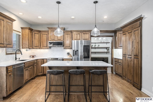 kitchen featuring a center island, a kitchen bar, light wood-type flooring, appliances with stainless steel finishes, and a sink