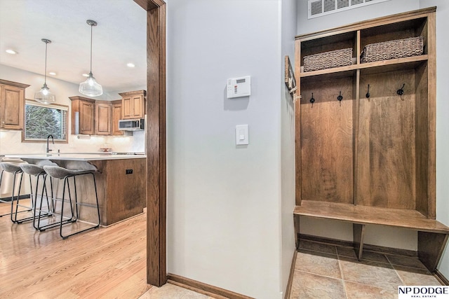 mudroom featuring recessed lighting, baseboards, and a sink