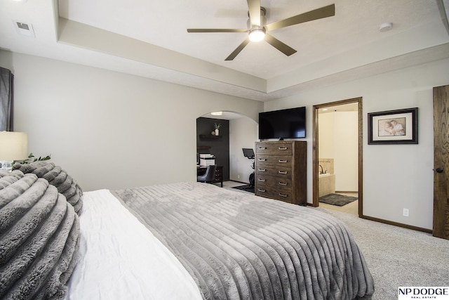 bedroom with visible vents, a tray ceiling, arched walkways, baseboards, and light colored carpet