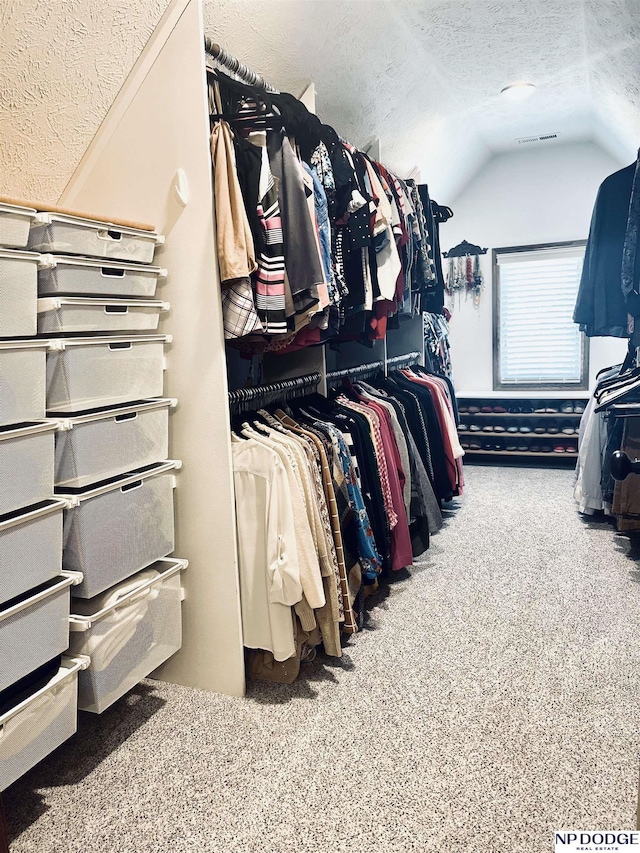 spacious closet with visible vents, carpet, and vaulted ceiling