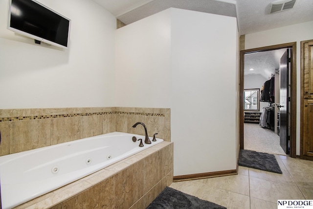 full bath featuring baseboards, visible vents, a whirlpool tub, a textured ceiling, and tile patterned floors