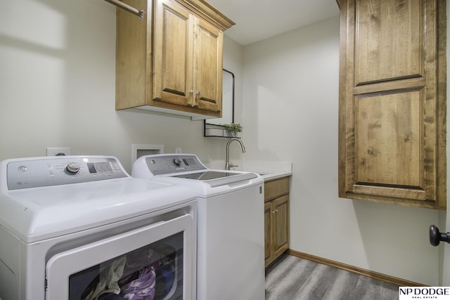 laundry area featuring light wood-type flooring, a sink, cabinet space, baseboards, and washing machine and clothes dryer