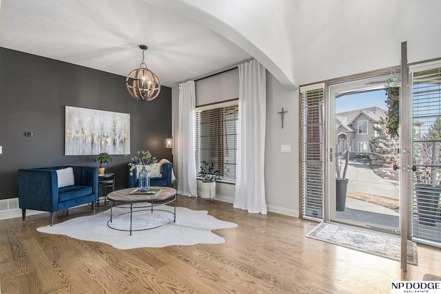 living area featuring baseboards, arched walkways, an inviting chandelier, and wood finished floors