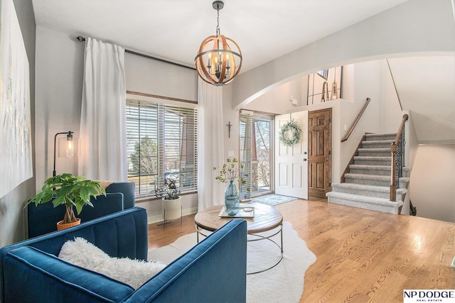 living room featuring arched walkways, stairs, an inviting chandelier, and wood finished floors