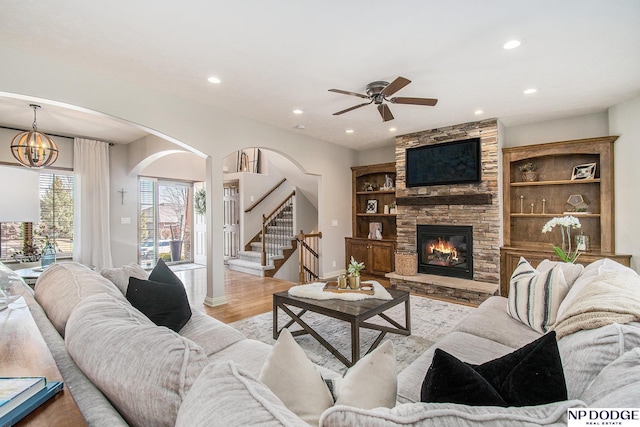 living room featuring recessed lighting, stairway, a stone fireplace, and light wood-style flooring