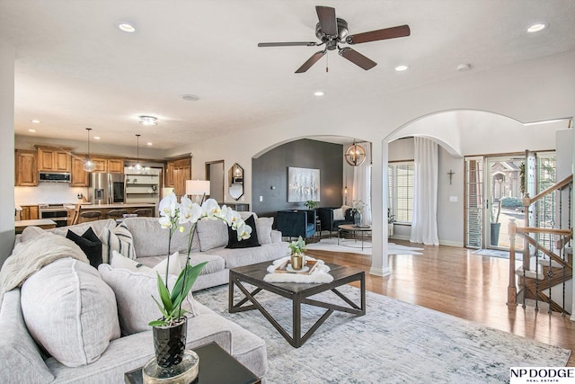 living room featuring baseboards, stairs, recessed lighting, light wood-style floors, and arched walkways