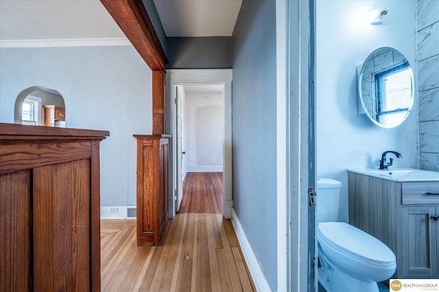 half bathroom featuring vanity, wood finished floors, visible vents, baseboards, and toilet