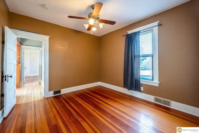 spare room featuring visible vents, baseboards, a ceiling fan, and hardwood / wood-style flooring