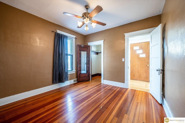 unfurnished bedroom with a spacious closet, visible vents, baseboards, and wood-type flooring