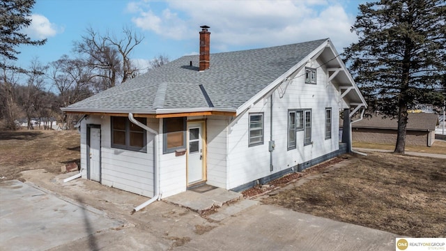 view of front of home with roof with shingles and a chimney