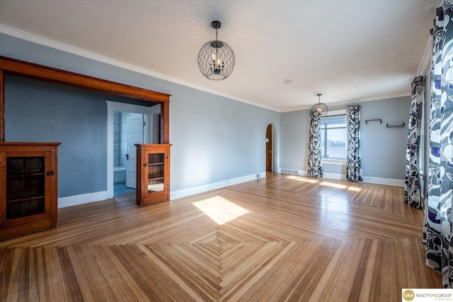 unfurnished living room with visible vents, baseboards, an inviting chandelier, arched walkways, and ornamental molding