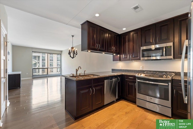 kitchen featuring light wood finished floors, visible vents, dark brown cabinets, appliances with stainless steel finishes, and a sink