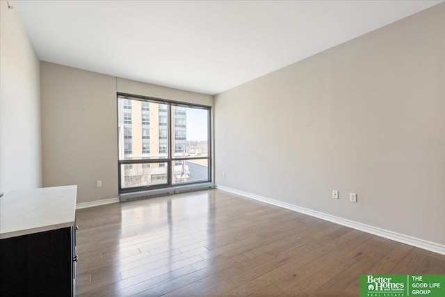 unfurnished living room with wood finished floors and baseboards