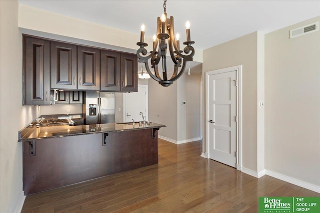 kitchen with visible vents, stainless steel refrigerator with ice dispenser, dark wood-style floors, dark brown cabinetry, and a peninsula