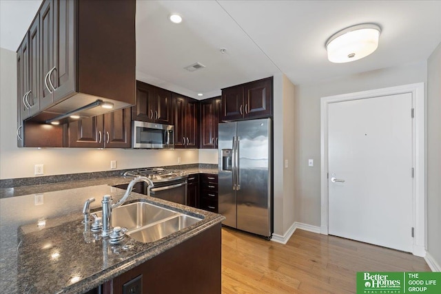 kitchen featuring dark stone countertops, visible vents, a sink, light wood-style floors, and appliances with stainless steel finishes