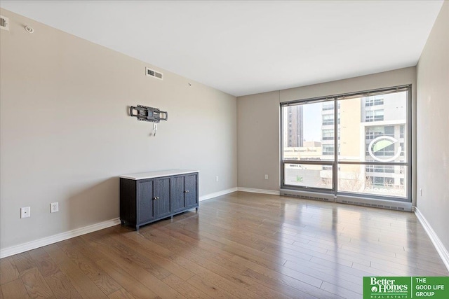 spare room featuring visible vents, baseboards, and wood finished floors