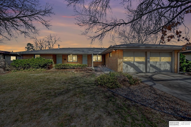 mid-century home with a front yard, an attached garage, brick siding, and driveway