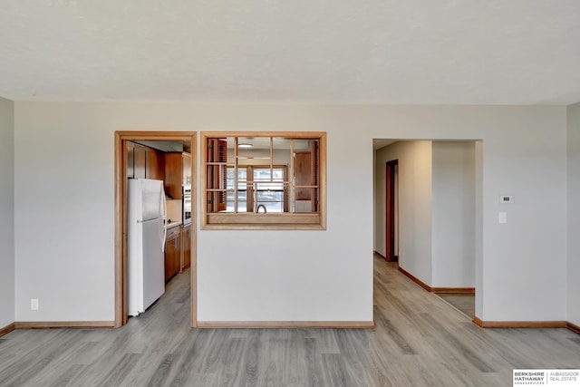 empty room featuring light wood-style flooring, visible vents, and baseboards