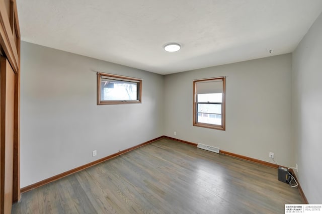 unfurnished bedroom with a closet, visible vents, baseboards, and wood finished floors