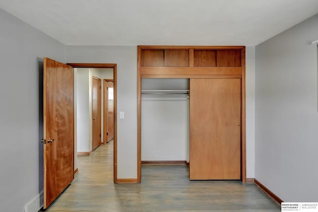 unfurnished bedroom featuring a closet, baseboards, and light wood finished floors