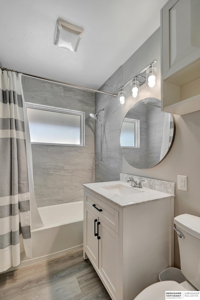 bathroom with vanity, toilet, wood finished floors, and shower / tub combo