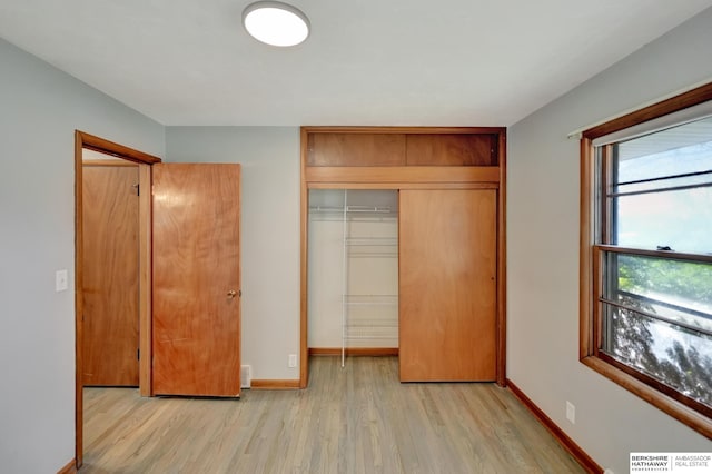 unfurnished bedroom with a closet, visible vents, light wood-type flooring, and baseboards