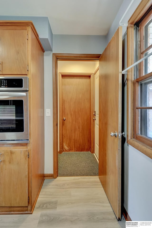 kitchen featuring stainless steel oven, light wood-style floors, and baseboards