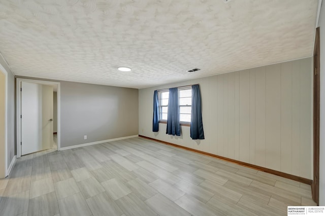 spare room with baseboards, visible vents, and a textured ceiling