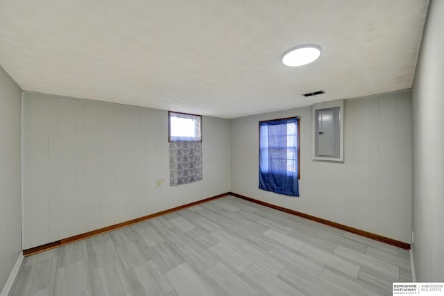 empty room featuring electric panel, visible vents, and baseboards