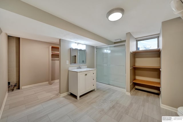 bathroom with baseboards, a spacious closet, a stall shower, and vanity