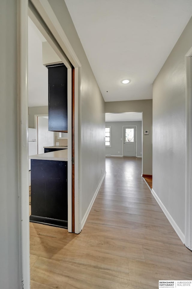 hall with light wood-style flooring and baseboards