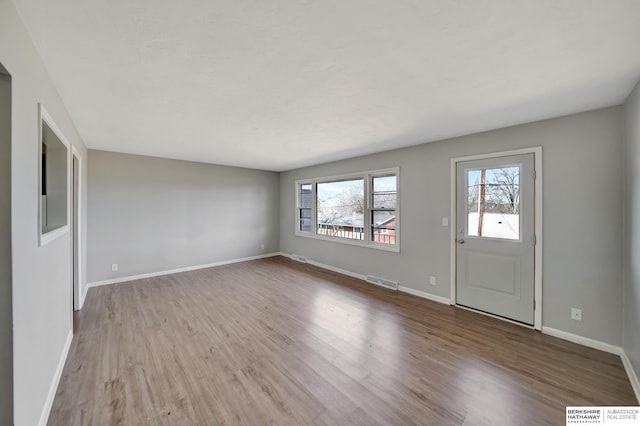 foyer entrance with wood finished floors, visible vents, and baseboards