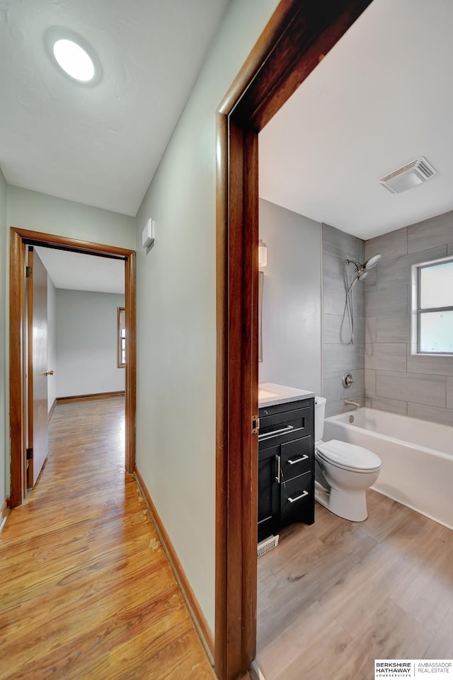 hallway featuring baseboards, visible vents, and light wood-type flooring