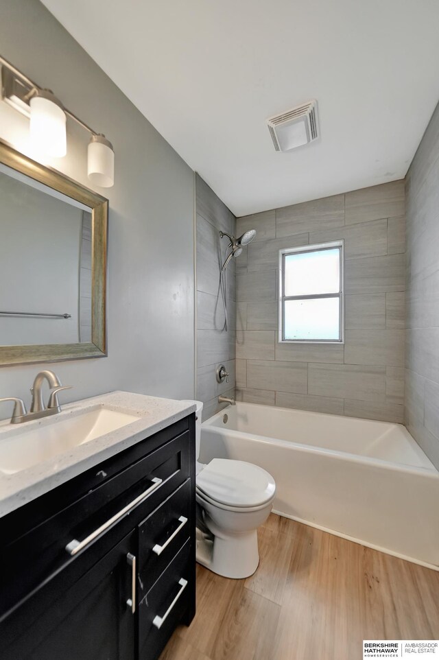 bathroom featuring vanity, wood finished floors, visible vents, shower / washtub combination, and toilet