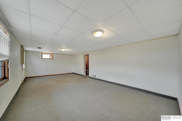 basement featuring carpet flooring, concrete block wall, a paneled ceiling, and visible vents