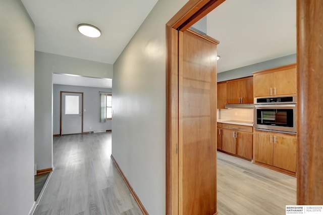 hall with baseboards and light wood-style flooring