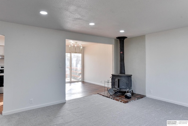 unfurnished living room with recessed lighting, baseboards, carpet, and a wood stove