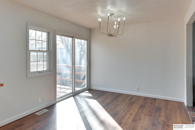 unfurnished dining area with an inviting chandelier, dark wood-style floors, visible vents, and baseboards