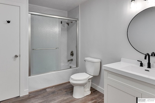 full bathroom featuring vanity, toilet, wood finished floors, and bath / shower combo with glass door