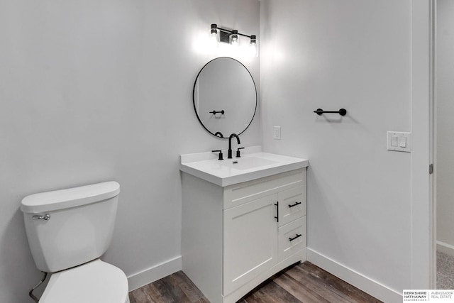 half bathroom featuring vanity, toilet, wood finished floors, and baseboards