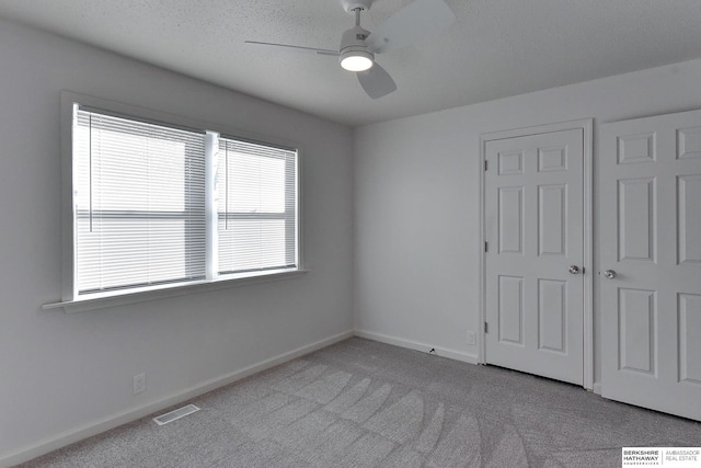 unfurnished bedroom with baseboards, visible vents, carpet floors, and ceiling fan