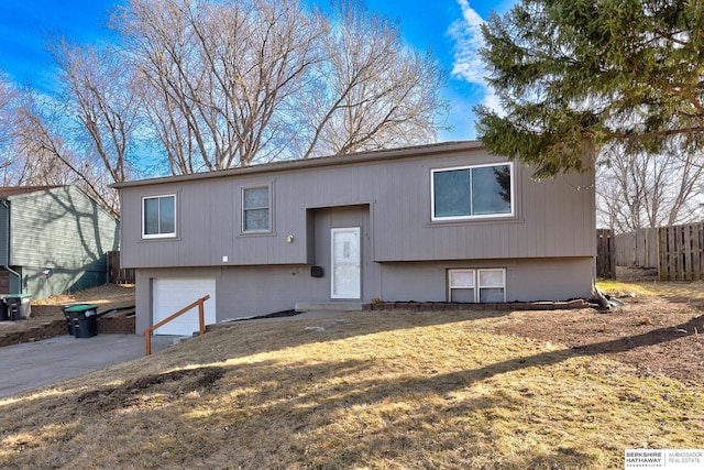 split foyer home featuring a garage, driveway, and fence