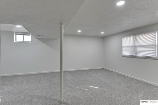 below grade area featuring visible vents, baseboards, carpet floors, recessed lighting, and a textured ceiling