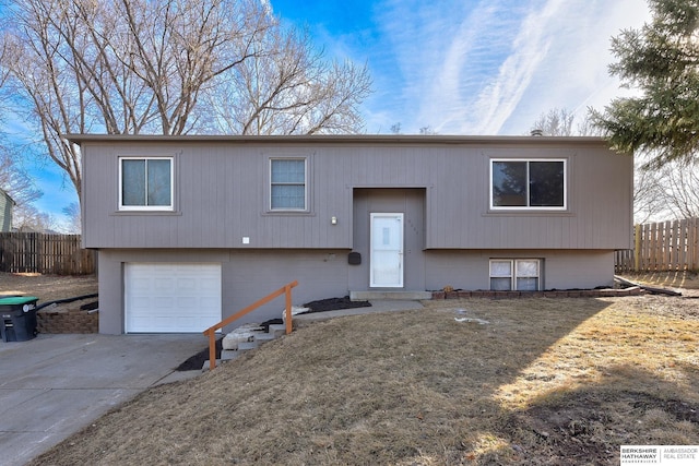 split foyer home with driveway, a garage, and fence