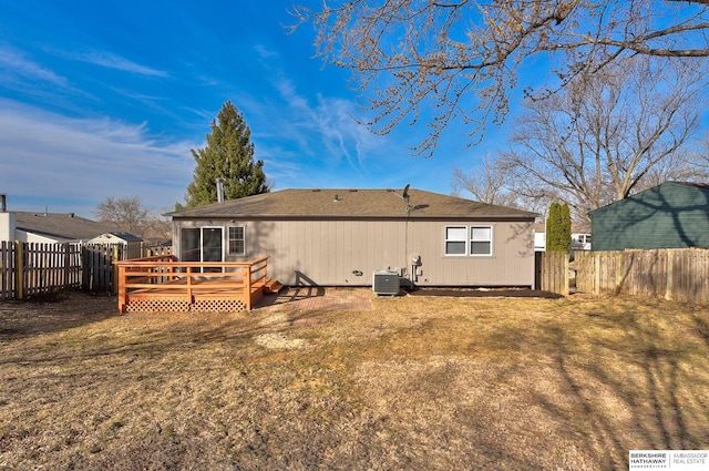 rear view of property with central air condition unit, a fenced backyard, a lawn, and a wooden deck