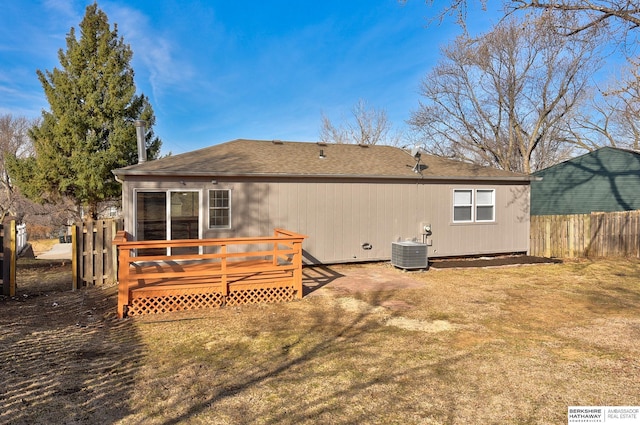 rear view of property featuring a shingled roof, fence, a wooden deck, central AC unit, and a yard