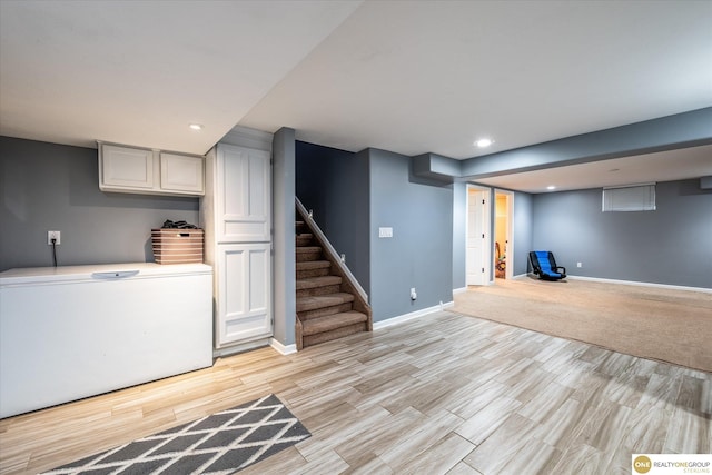 finished basement featuring light wood-style floors, recessed lighting, stairs, and baseboards