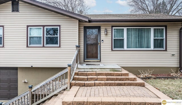 property entrance featuring a garage and a shingled roof